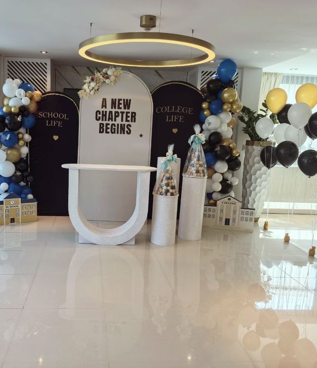 Celebration hall with an aisle of gold and navy balloon bouquets leading to the college send-off stage — Zaina Events Abu Dhabi