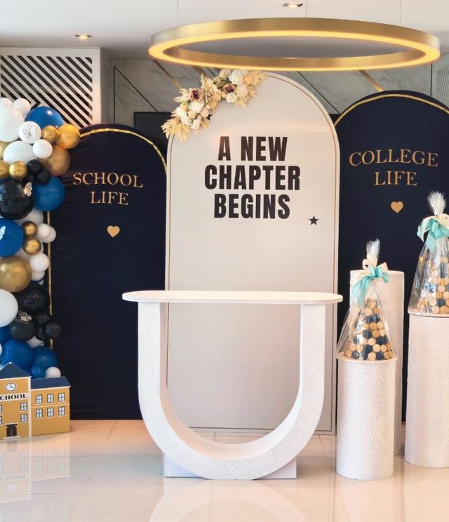College send-off stage with navy and white arches and gold-and-blue balloon columns — Zaina Events Abu Dhabi